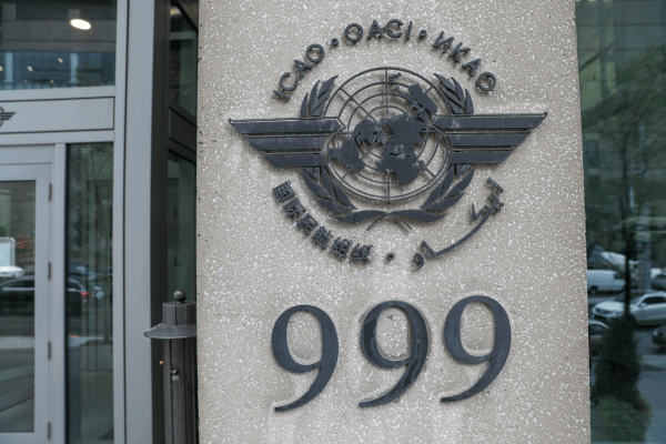 Stone building plaque displaying the International Civil Aviation Organization emblem above the number 999, near an entrance with glass doors.